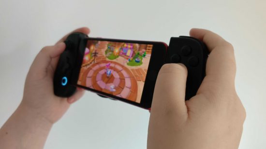 Black Friday controller deals - Two white hands holding the LeadJoy M1 iPhone controller at an angle while playing Hello Kitty Island Adventure