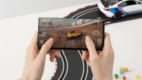 Samsung actively involved in ray-tracing on mobile: A promotional image of someone playing a racing game on the Samsung Galaxy S23 Ultra. Behind them is a white table with a remote control car track on it.