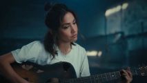 Screenshot from the Samsung ad, Uncrush, with a woman playing guitar among the remnants of the Apple crush