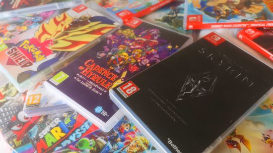Switch games in a pile, with Skyrim, Pokémon Shield, and Cadence of Hyrule near the top. Yooka-Laylee and the Impossible Lair, Super Mario Odyssey, Tears of the Kingdom, and Donkey Kong Country: Tropical Freeze are also visible.
