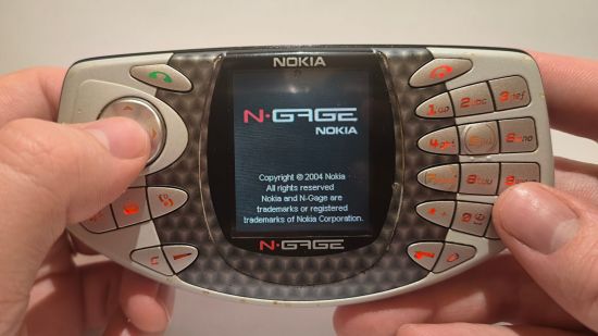 Custom image for Nokia N-Gage review with the reviewer holding the device in the hands with a thumb on the d-pad
