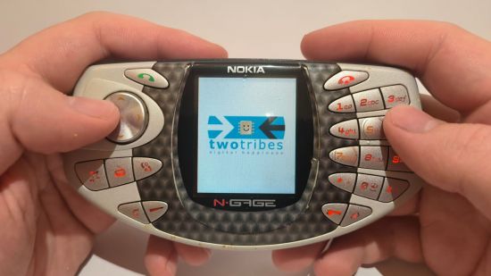 Custom image for Nokia N-Gage review showing the reviewer loading a game with hands on the device