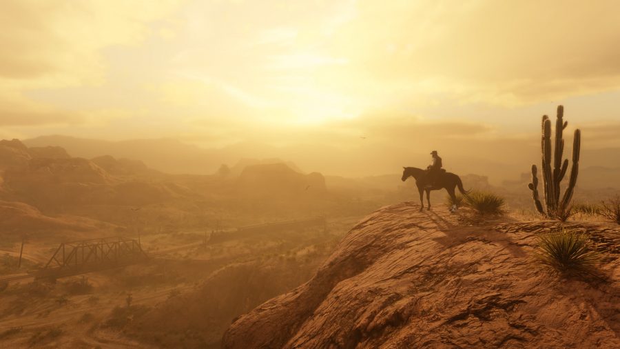 Cowboy sat on a horse overlooking a sunset in Red Dead Redemption 2