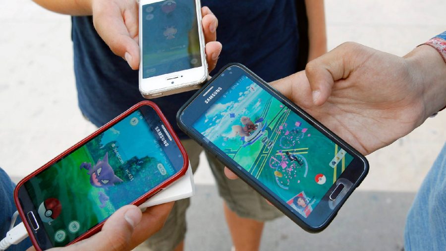 Pokemon Go sixth anniversary interview: several phones are hgeld together in a photograph, all with Pokemon Go on the screen